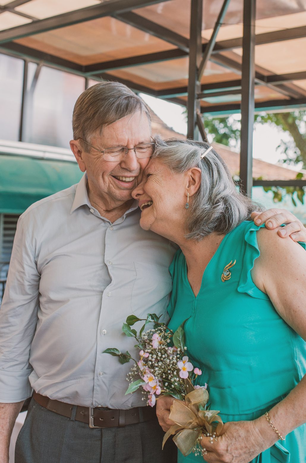 A couple laughing together, holding a small bouquet