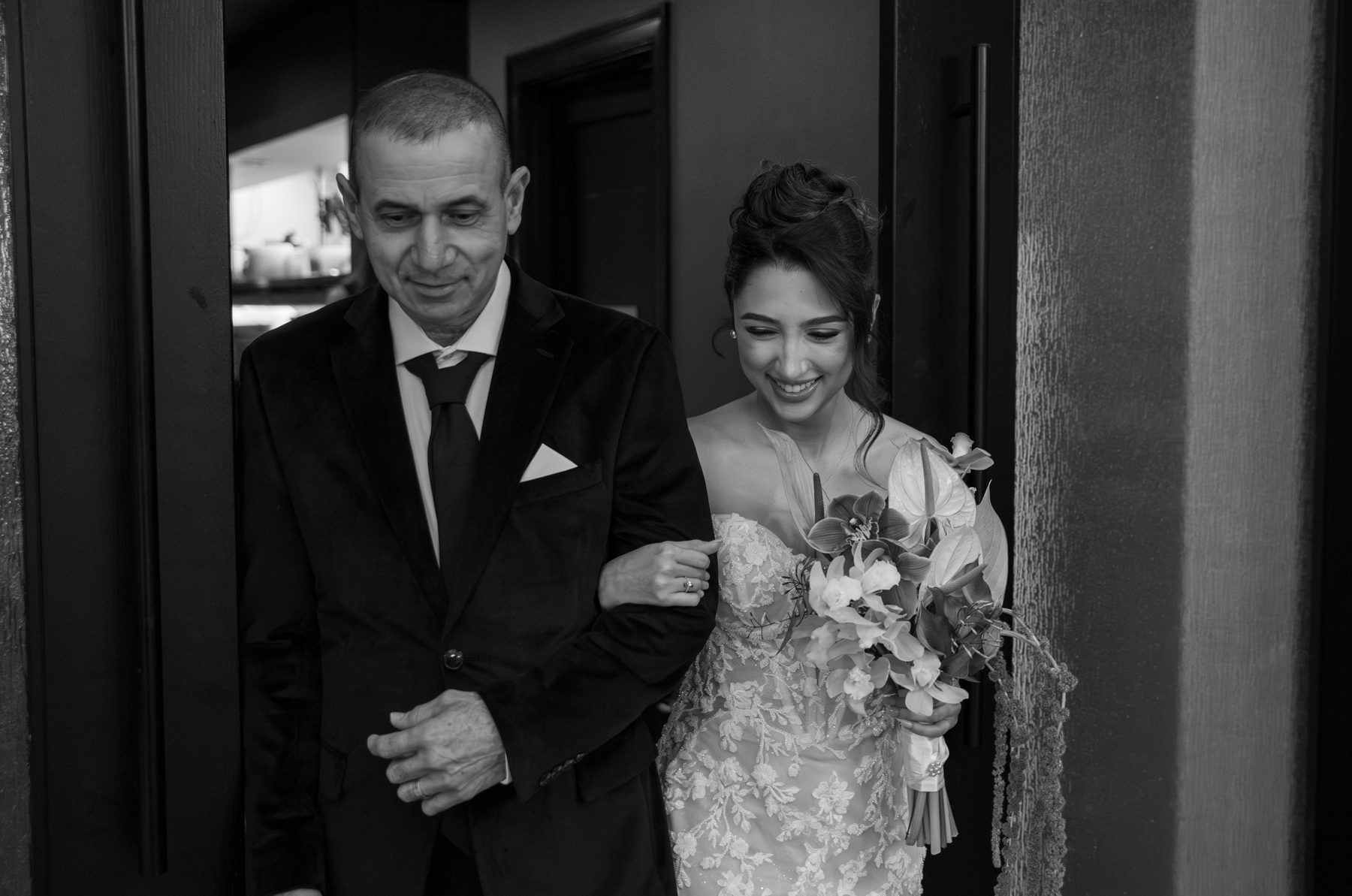 Black and white photo of a father walking the bride in